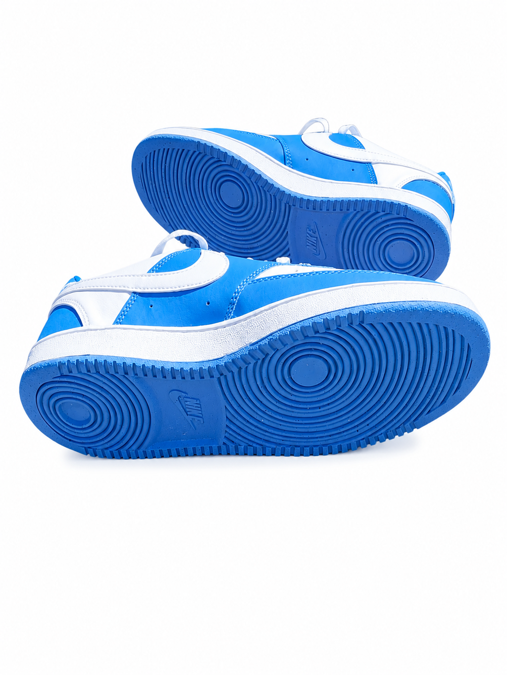 A pair of Nike low-top sneakers in a vibrant blue and white colorway, showing the side profile and the textured blue outsoles with a visible Nike logo.