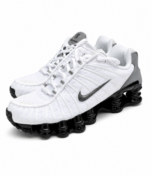 A pair of Nike Shox sneakers in white with a textured pattern, featuring a dark gray Swoosh and a black spring-loaded sole, shown on a white background.